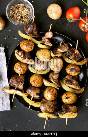 Huhn Leber und Gemüse Spieße auf schwarzen Hintergrund. Ansicht von oben, flach Stockfoto