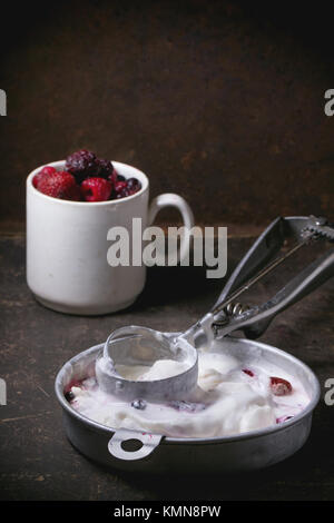 Aluminium-Platte mit Vanilleeis und Tasse gefrorene Beeren serviert mit Metalllöffel über dunklen Tisch. Serien ansehen Stockfoto