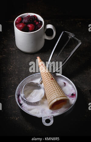 Platte aus Aluminium mit Vanilleeis, Mix aus gefrorenen Beeren und waffer Kegel, serviert mit Metall Löffel über Metall Tisch. Siehe Serie Stockfoto