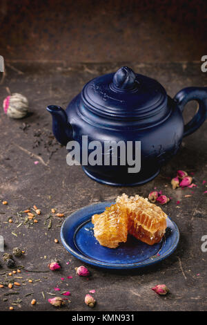 Blau Keramik Teekanne und Platte mit Waben, mit schwarzen und grünen Tee serviert Leben in dunklen Hintergrund. Chinesische Inschrift auf Teekanne - traditionelle Stockfoto