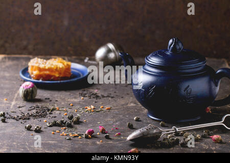 Blau Keramik Teekanne und Platte mit Waben, serviert mit Löffel, schwarzer und grüner Tee leben in dunklen Hintergrund. Chinesische Inschrift auf Teekanne-tra Stockfoto