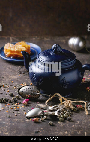 Blau Keramik Teekanne und Platte mit Waben, serviert mit Löffel, schwarzer und grüner Tee leben in dunklen Hintergrund. Chinesische Inschrift auf Teekanne-tra Stockfoto