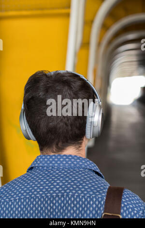 Rückansicht des Menschen im urbanen Umfeld mit Kopfhörern Stockfoto