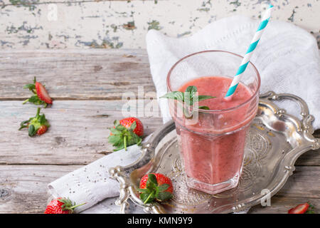 Glas rote Erdbeere Smoothie mit Chia-Samen, serviert mit retro cocktail Rohr, frischer Minze und Erdbeeren über Holztisch Stockfoto