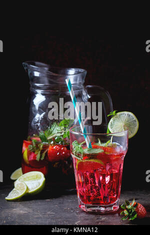 Glas mit retro Cocktail Rohre und glaskanne von Erdbeer Limonade, serviert mit frischen Erdbeeren, Minze und Limette über dunklen Hintergrund. Siehe Serie Stockfoto