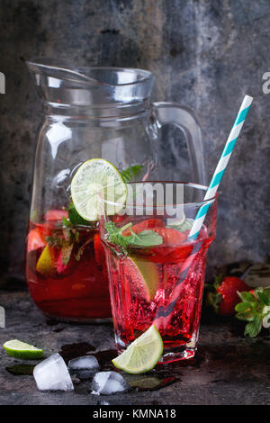 Glas mit retro Cocktail Rohre und glaskanne von Erdbeer Limonade, serviert mit frischen Erdbeeren, Minze und Limette über dunklen Hintergrund. Siehe Serie Stockfoto