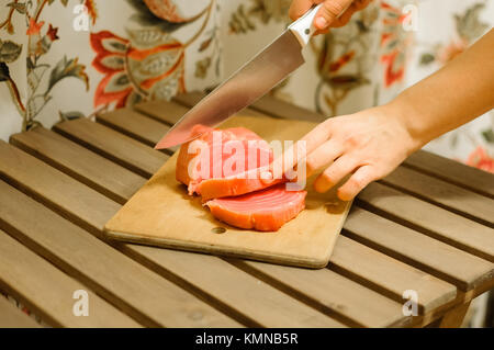 Frau schneiden frisches Lachsfilet auf Holzbrett Stockfoto