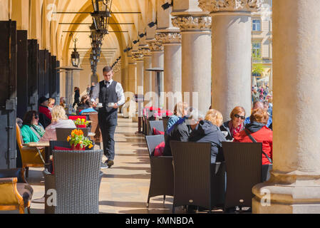 Krakau Café, Touristen auf der Terrasse des Cafés in der Säulenhalle des historischen Tuchhallen - sukiennice - in Krakau, Polen, entspannen. Stockfoto