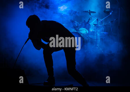 Silhouette einer Sängerin mit einem Mikrofon auf einem Konzert auf dem Hintergrund der Trommeln in Rauch mit blauer Beleuchtung Stockfoto