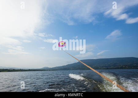 Fallschirm Segelflug segeln Frau von Seil zu Boot über den See Gewässer Landschaft Landschaft angebracht gezogen. Stockfoto