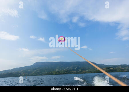 Fallschirm Segelflug segeln Frau von Seil zu Boot über den See Gewässer Landschaft Landschaft angebracht gezogen. Stockfoto