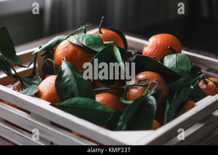 Holzkiste für frische Mandarinen mit Blättern Stockfoto