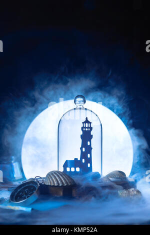 Meer Stillleben mit Leuchtturm Silhouette in Vollmond. Nacht Ozean Szene mit Rauch auf dem Wasser und Kopieren. Konzeptionelle Paper Craft. Stockfoto