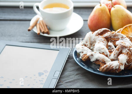 E-Book und Bayerische Creme puff mit zerquetschten Haselnuss und Zitrone fudge auf einem blauen Schild. Im Hintergrund ist eine Tasse grünen Tee und Birnen. Stockfoto