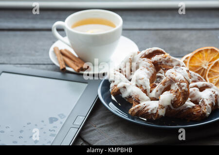 E-Book und Bayerische Creme puff mit zerquetschten Haselnuss und Zitrone fudge auf einem blauen Schild. Im Hintergrund eine Tasse grüner Tee und Zimtstangen. Stockfoto