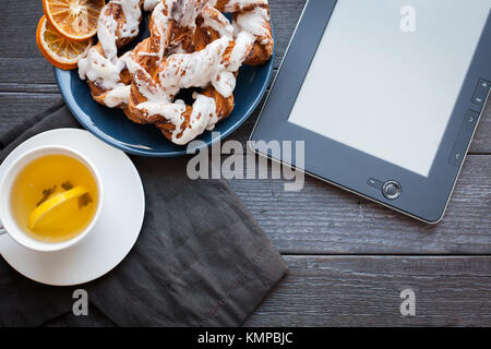 E-Book und Bayerische Creme puff mit zerquetschten Haselnuss und Zitrone fudge auf einem blauen Schild. Im Hintergrund eine Tasse grünen Tee mit Zitrone und Zimt sti Stockfoto