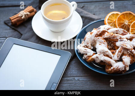 E-Book und Bayerische Creme puff mit zerquetschten Haselnuss und Zitrone fudge auf einem blauen Schild. Im Hintergrund eine Tasse grünen Tee mit Zitrone und Zimt sti Stockfoto