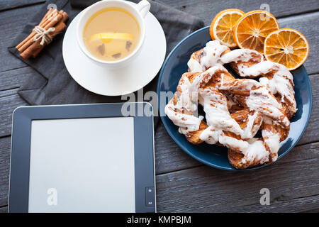 E-Book und Bayerische Creme puff mit zerquetschten Haselnuss und Zitrone fudge auf einem blauen Schild. Im Hintergrund eine Tasse grünen Tee mit Zitrone und Zimt sti Stockfoto