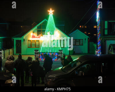 Warden Bay, Kent, Großbritannien. 8 Dez, 2017. Ein Haus in Warden Bucht setzt auf eine beeindruckende Weihnachtsbeleuchtung Anzeige mit einem Weihnachtsbaum größer als das Haus von der Beleuchtung, die eine Reihe von Computer-gesteuerte Muster gebildet. Jeden Freitag im Dezember vor Weihnachten eine kurze Anzeige auf ist für Einheimische um 19.00 Uhr, mit den Lichtern zu Musik eingestellt. Heute Abend sogar auf den außergewöhnlich kalten Abend, rund 50 Personen kam heraus zu beobachten. Die Anzeige ist von Daniel und Kelly Arnott mit Spenden aufgebracht für Nächstenliebe organisiert. Credit: James Bell/Alamy Leben Nachrichten. Stockfoto