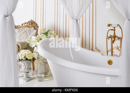 Luxuriöses Badezimmer in hellen Farben mit goldenen Möbel Details und Vordach. Elegantes, klassisches Interieur Stockfoto