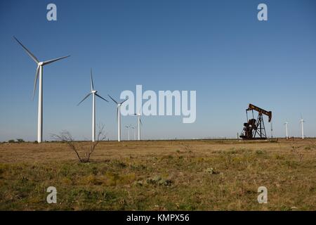 Reihen von Windturbinen und ein Rohölpumpenheber auf leerem Ackerland im ländlichen West Texas, USA Stockfoto