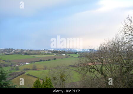 Winter Land Blick vom Hügel über Bäume in Richtung Felder und offene Landschaft mit Schnee gefüllt Himmel in South Herefordshire England Großbritannien Stockfoto