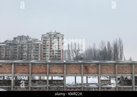 Kommunistische Gehäuse Gebäude vor einem verlassenen Lagerhalle in Pancevo, Serbien, während eines kalten Nachmittag unter dem Schnee. Diese Art der Türme sind ein s Stockfoto