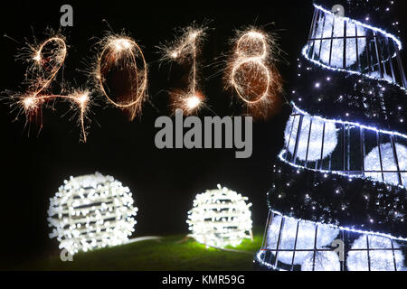Isolierte 2018 Zeichen geschrieben mit Schein Feuerwerk und geschmückten Weihnachtsbaum auf dem schwarzen Hintergrund, neues Jahr 2018 Konzept zufrieden. Stockfoto