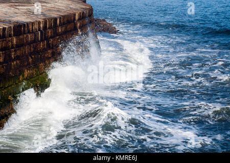 Wellen gegen die Hafenmauer. Stockfoto