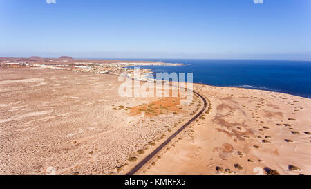 Luftaufnahme der Straße durch weißen Sandstrand, Dünen in Richtung Ferienort Corralejo, Fuerteventura, Kanarische Inseln, Spanien. Stockfoto