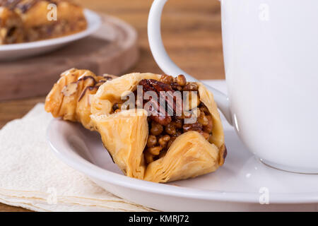 Nahaufnahme von Baklava auf einem weißen Teller mit Kaffeetasse Stockfoto