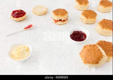 Anordnung der frisch gebackenen Scones, clotted cream und Erdbeermarmelade auf Weiß marmorierten Hintergrund mit kopieren. Schrägansicht. Stockfoto