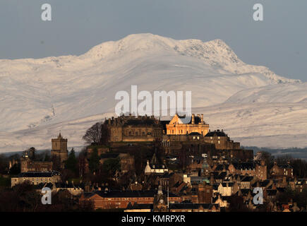 Blick auf die Burg Stirling am frühen Morgen Sonnenschein mit den schneebedeckten Stuc ein 'Chroin Berg im Hintergrund. Stockfoto