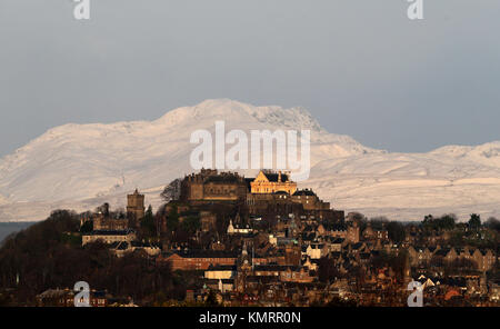 Blick auf die Burg Stirling am frühen Morgen Sonnenschein mit den schneebedeckten Stuc ein 'Chroin Berg im Hintergrund. Stockfoto