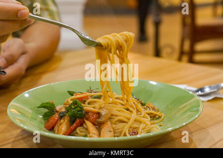 Stir-Fried Spaghetti mit Olivenöl, Knoblauch, getrocknete Chilis und knusprigem Speck, Hand halten Sie die Gabel roll Spagetti Stockfoto
