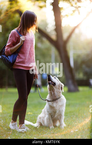 Bild der jungen Frau zu Fuß mit Retriever im Sommer Park Stockfoto