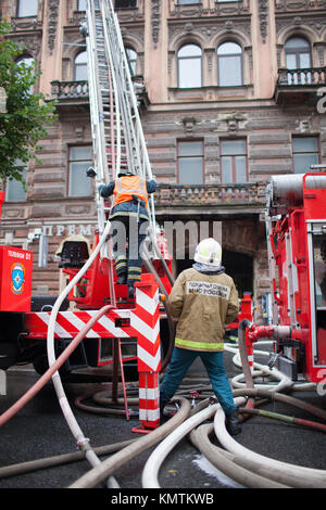 Sankt Petersburg, Russland, am Morgen des 13. September 2017. Feuerwehrmänner ein großes Feuer auf dem Dach eines Wohnhauses löschen auf der Straße Stockfoto