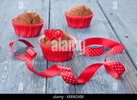Chocolate Muffins in rot Pappbecher mit Herzen und ein Band eingerichtet Stockfoto