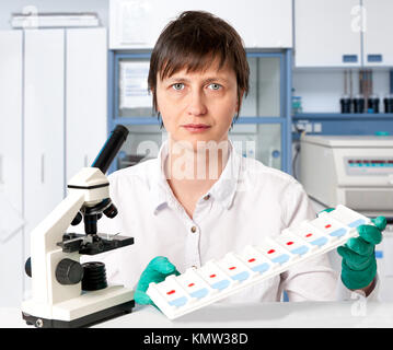 Histologe mit einem Mikroskop und ein Fach der mikroskopischen Objektträger auf weißem Hintergrund Stockfoto