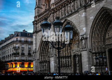 Am frühen Abend außerhalb der Kathedrale Notre Dame in Paris Frankreich mit einem blauen Himmel, Lampenhalter und Cafe leuchtet Stockfoto