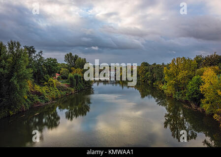 Auf der Suche nach unten von der Brücke den Fluss mit schönen Reflexionen von grünen Bäumen, unter blauem Himmel mit Fluffy Clouds Stockfoto