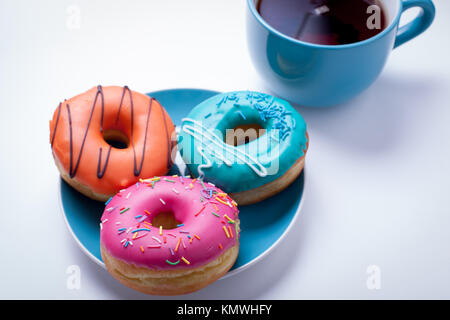 Eine Tasse Tee und eine Platte mit Donuts in einer Glasur auf einem weißen Hintergrund. Stockfoto