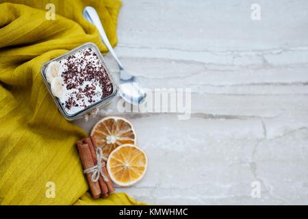 Cremiger Pudding mit einer Banane, Schokolade und Zimt auf einem Marmor Hintergrund. Leichtes Frühstück. Ansicht von oben. Stockfoto