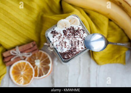 Cremiger Pudding mit einer Banane, Schokolade und Zimt auf einem Marmor Hintergrund. Leichtes Frühstück. Ansicht von oben. Stockfoto