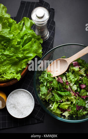 Frische vegetarische Salat Mix in einer klaren Glasgefäß auf schwarzem Hintergrund. Ansicht von oben. Stockfoto