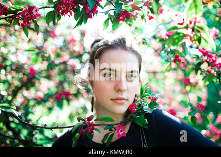 Portrait einer jungen schönen Mädchen in einem blühenden Baum. Schönheit der Frühling ohne Allergie. Stockfoto