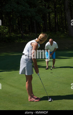 Eine Frau nimmt einen Schuß an einem Golfkurs in Massachusetts, USA. Stockfoto