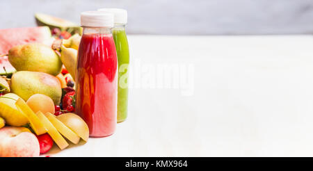 Flaschen mit Smoothies und Säfte Getränke auf weißem Hintergrund mit Sommer Früchte und Beeren, Vorderansicht, Banner. Gesunde Ernährung und vegetarische Stockfoto