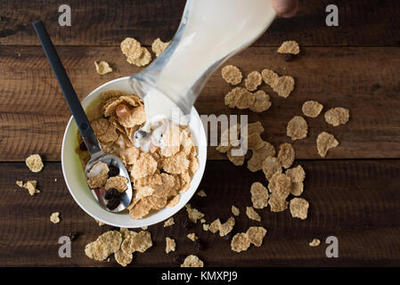 Gießen Milch in Frühstückscerealien (Cornflakes). gesunde Ernährung Konzept Stockfoto