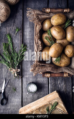 Kartoffeln mit Rosmarin auf rustikalen Holzmöbeln Hintergrund aus der Sicht von oben Stockfoto